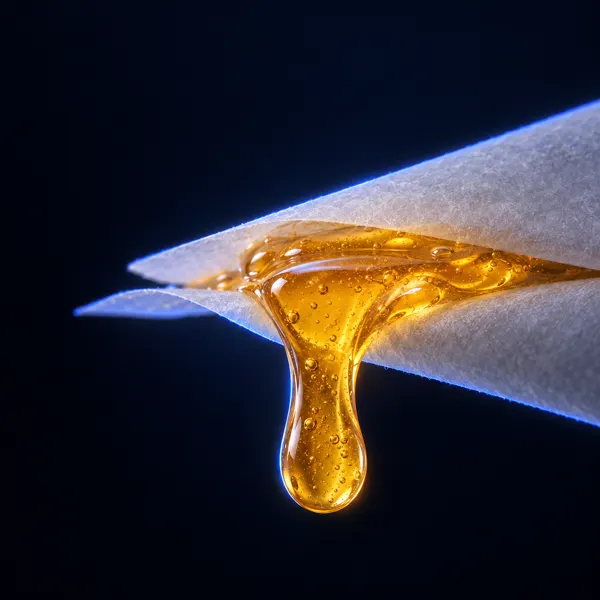 Gota de live rosin âmbar a escorrer entre duas folhas de papel vegetal
