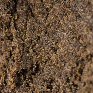 Macro do Moroccan Hash 60% THCX, grão seco e arenoso castanho-escuro