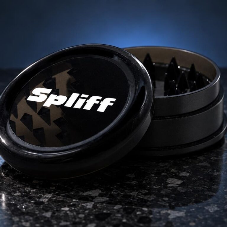 Grinder Mini preto em alumínio com tampa aberta, mostrando compartimentos internos, sobre superfície escura