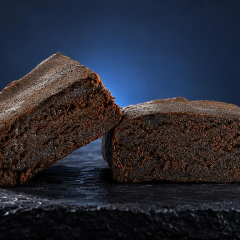 Dois blocos compactos de Tipos de haxixe com textura granulosa castanha, sobre superfície escura
